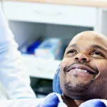 A man in a dentist's chair smiling