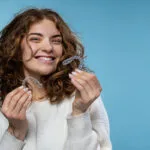 A woman is holding Invisalign trays